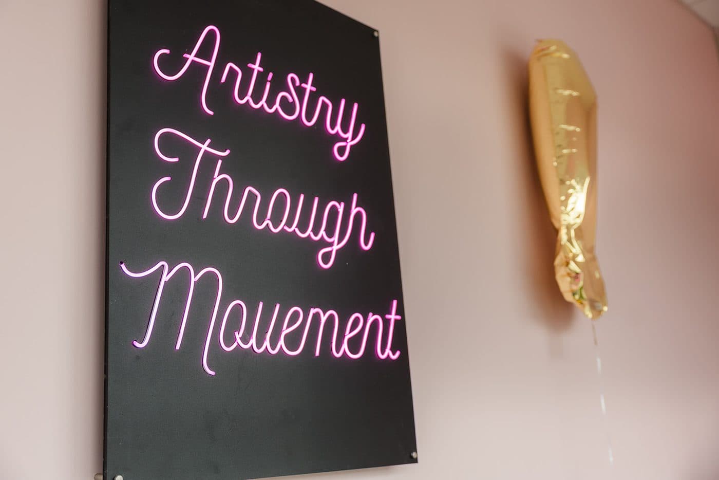 Artistry Through Movement neon sign in the studio