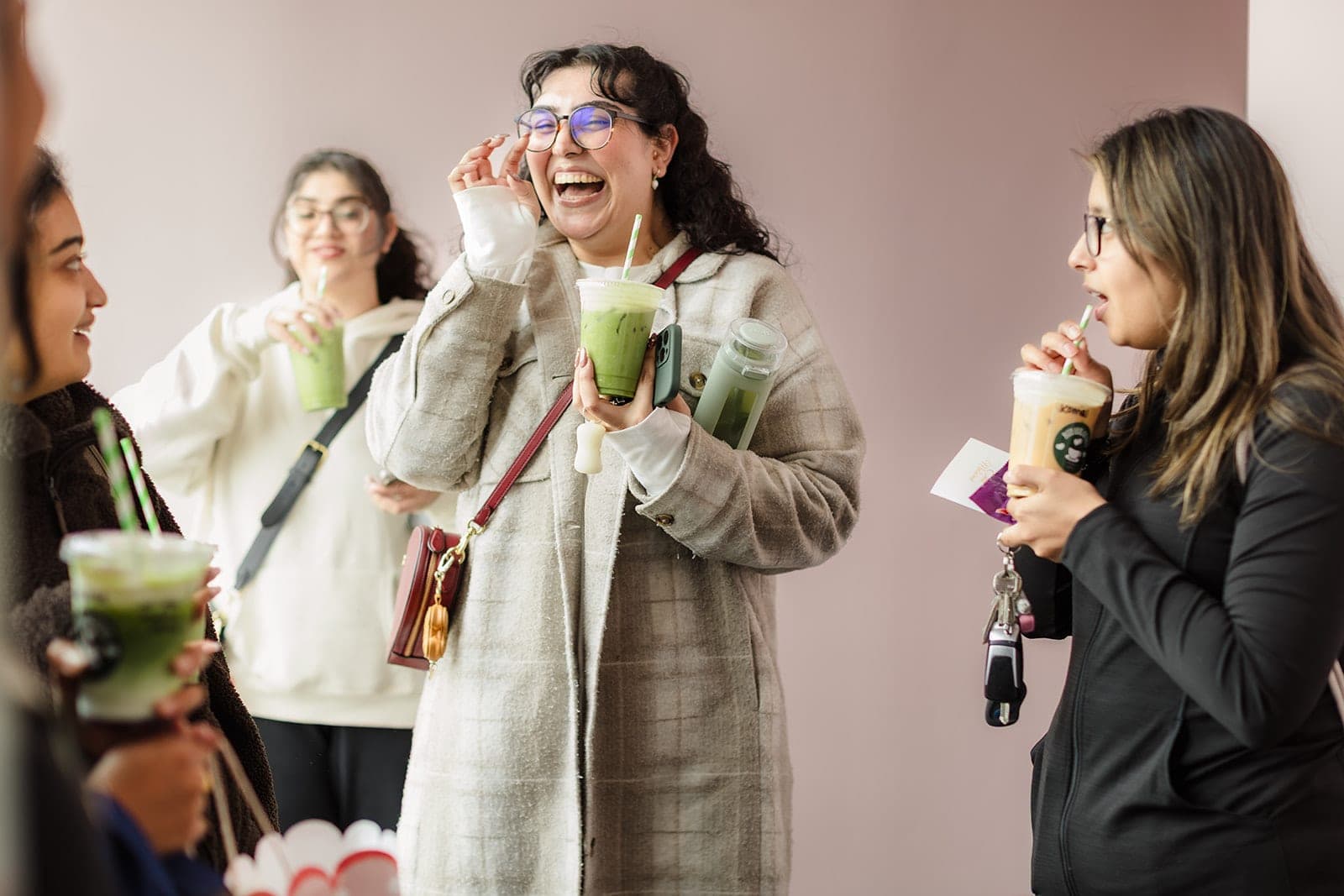 Women laughing together with matcha lattes after class