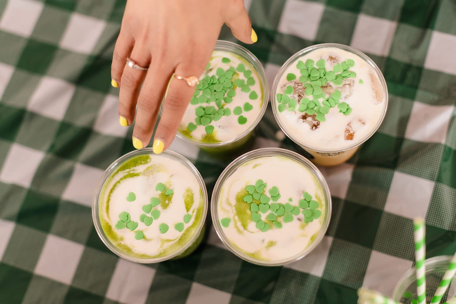 Iced matcha lattes topped with green heart sprinkles on green gingham