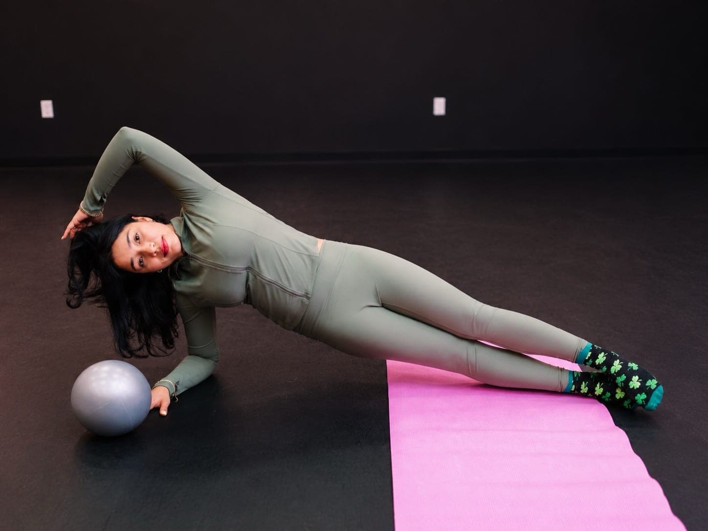 Rubabilattes instructor in a side plank on a pink mat